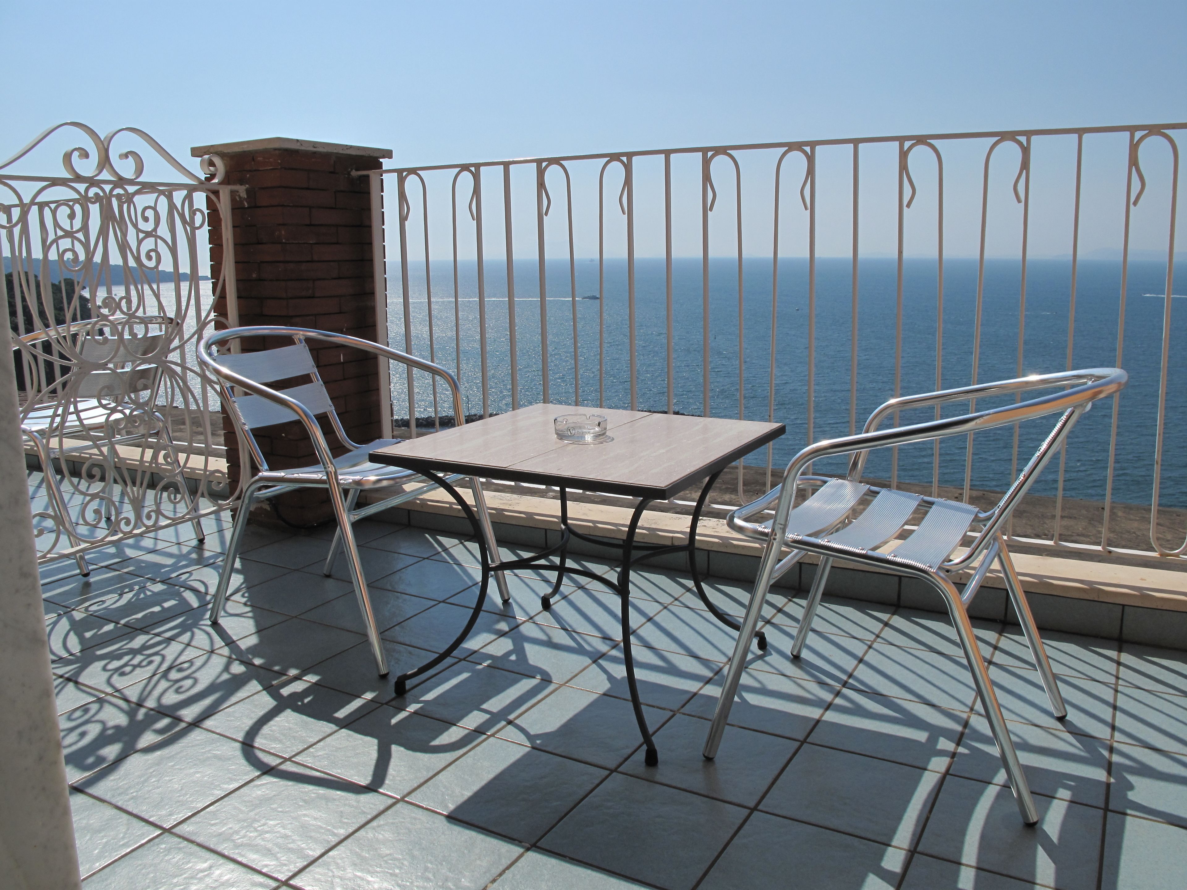 A balcony with a table and chairs, overlooking a body of water.