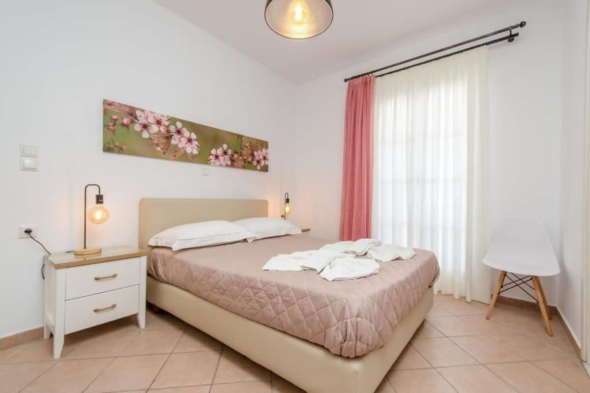 A bedroom with a bed, bedside tables, a lamp, a chair, and a window with curtains.