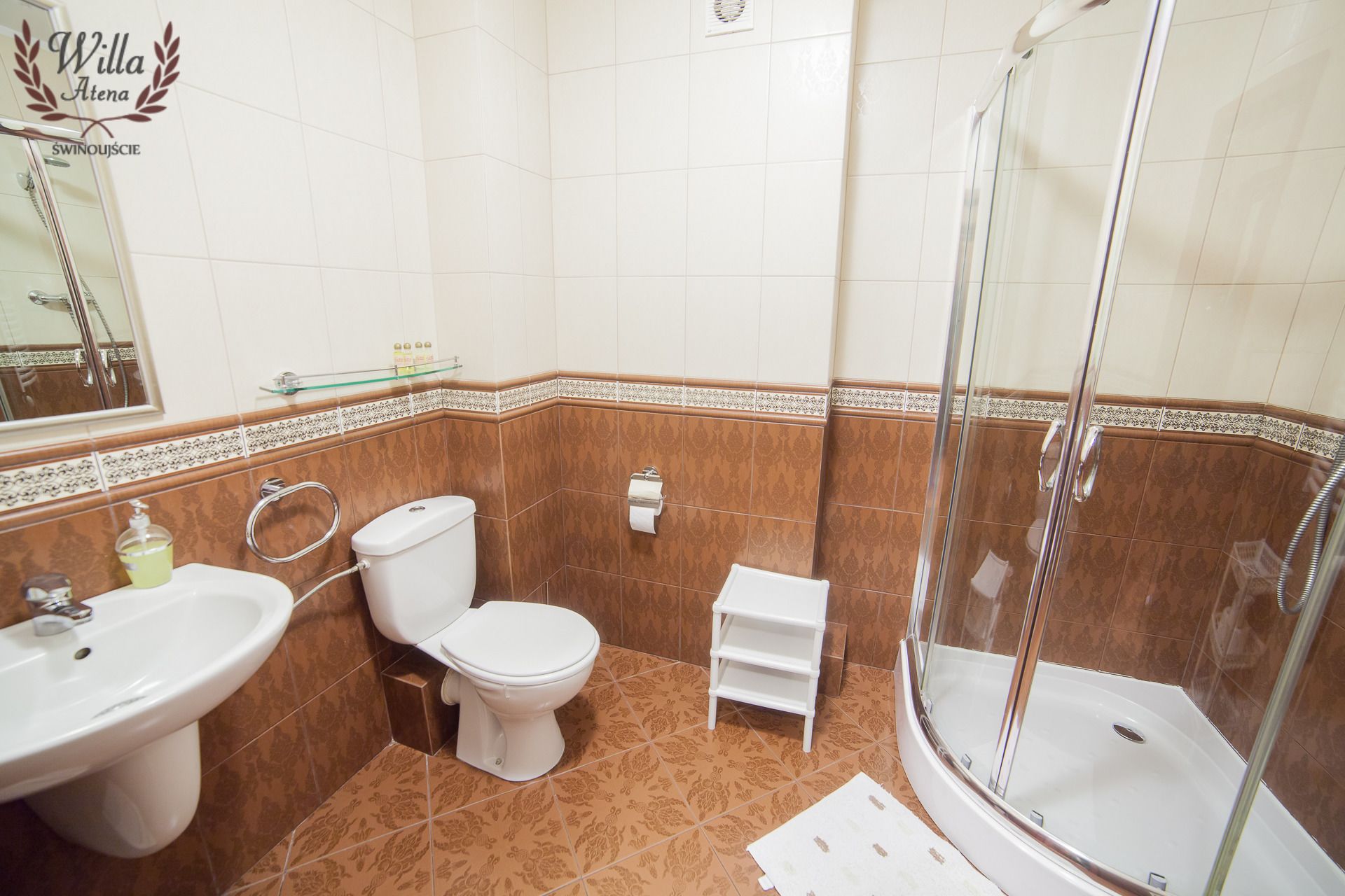 Un baño con ducha, inodoro, lavabo y un pequeño estante.