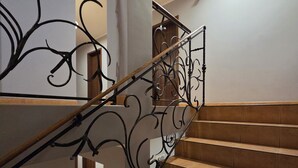 A staircase with ornate black metal railings and beige tiled steps. - Willa Atena (Swinoujscie)