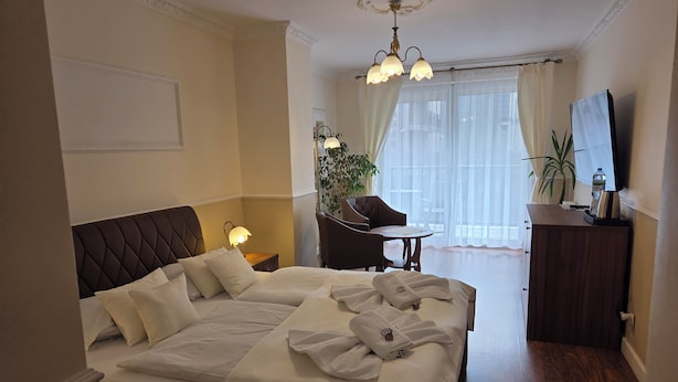 A hotel room with a large bed, a desk, a chair, a TV, and a plant. - Willa Atena (Swinoujscie)