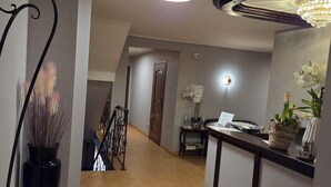 A hotel lobby with a reception desk, a staircase, and a chandelier. - Willa Atena (Swinoujscie)