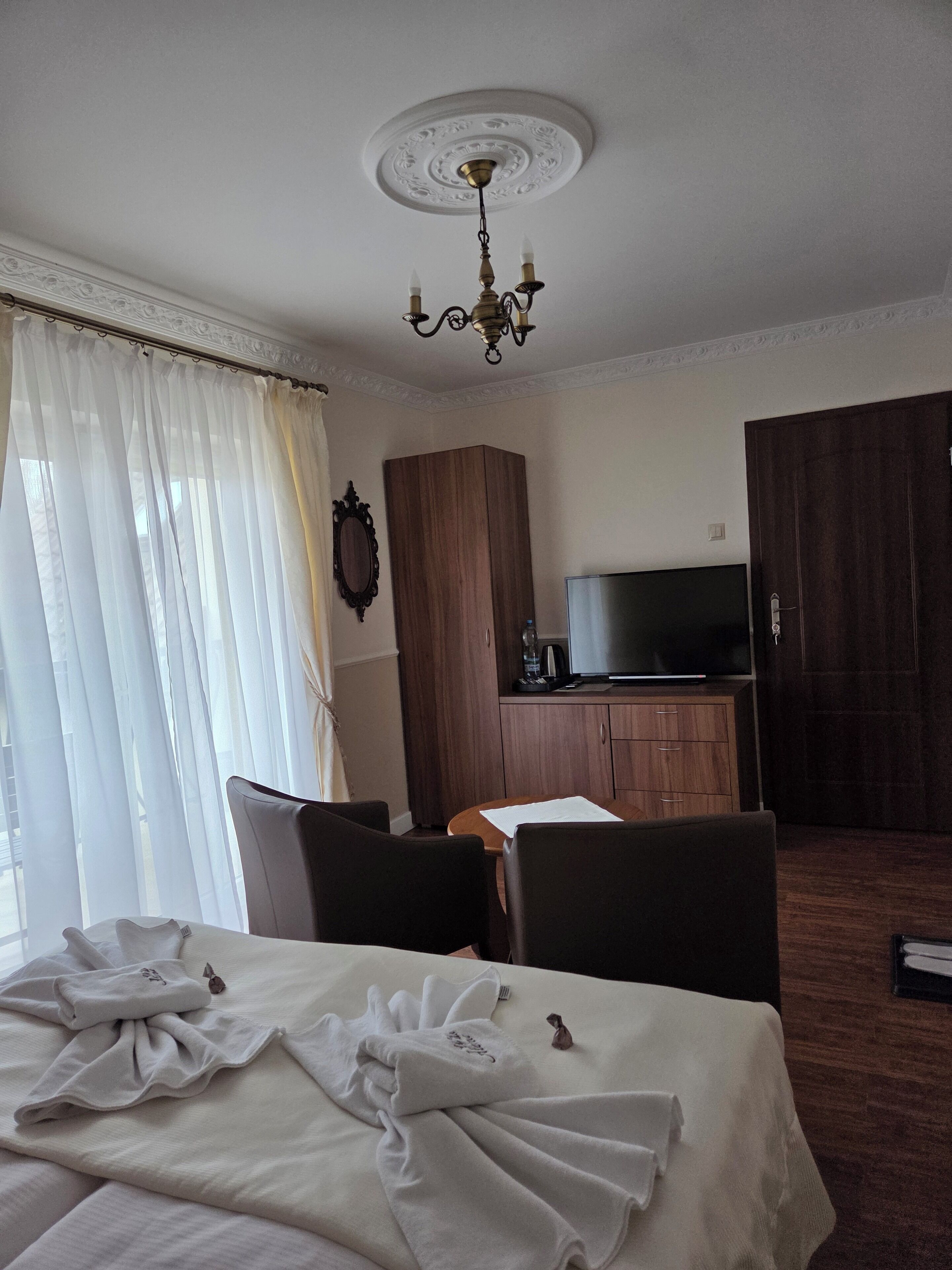 Una habitación de hotel con cama, escritorio, televisión y armario.