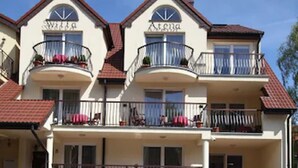 A multi-story hotel with balconies, a red roof, and a visible antenna. - Willa Atena (Swinoujscie)