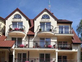 Um hotel de vários andares com varandas, telhado vermelho e antena visível.