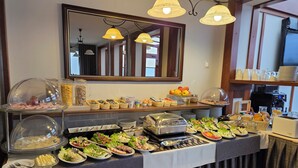 A buffet setup with various food items and utensils, a coffee machine, and a mirror above the counter. - Willa Atena (Swinoujscie)