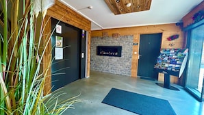 A reception area with a stone wall, a wooden ceiling, and a display of brochures. - Résidence les Thermes Côté Chalet (Thonon-les-Bains)