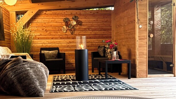A wooden interior with a hot tub, a dining area, and a cozy seating arrangement. - Résidence les Thermes Côté Chalet (Thonon-les-Bains)