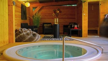 Interior de una cabaña de madera con hidromasaje, zona de estar y chimenea.