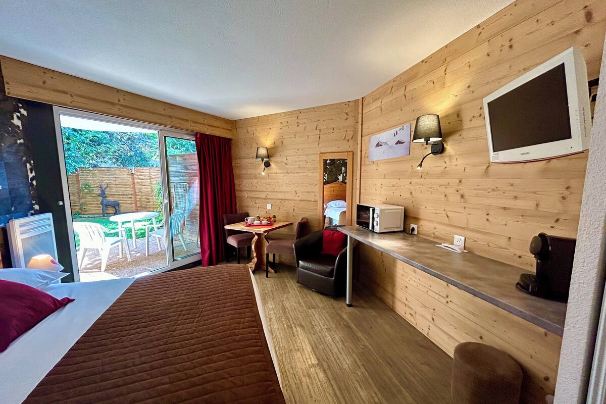 A hotel room with a bed, a dining table with chairs, a microwave, and a TV.