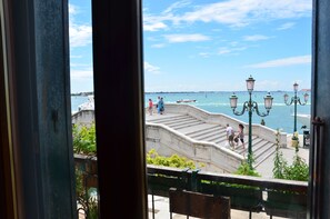 A view of a waterfront promenade with steps leading down to the water, benches, and street lamps. - Casa Favaretto (Venice)