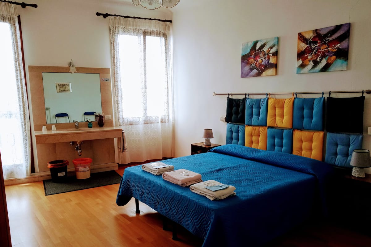 A bedroom with a bed, a dresser, a mirror, and a window with curtains.
