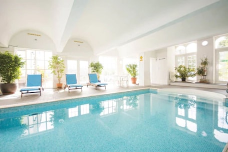 Una piscina techada, sillones reclinables de piscina. The Manor Hotel