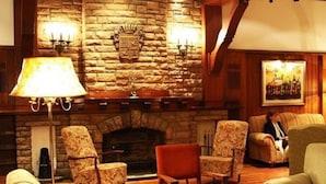 Een gezellige kamer met een stenen openhaard, gestreepten fauteuils en een vloerlamp.