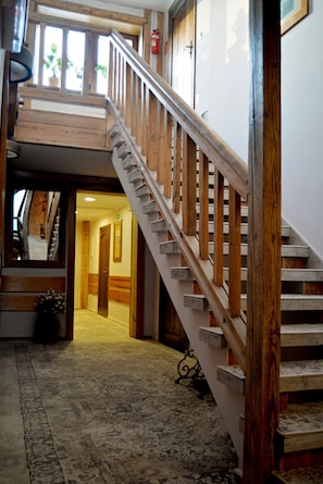 A wooden staircase with a handrail leading to an upper level. A carpeted hallway is visible below. - Karczma Chelminska (Chelmno)