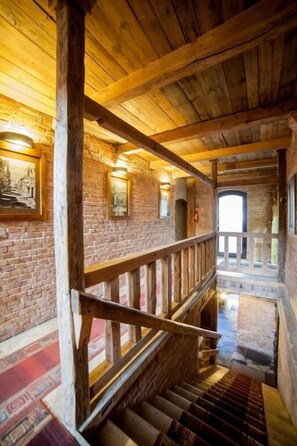 Una escalera de madera con barandilla de madera, paredes de ladrillo y cuadros enmarcados.