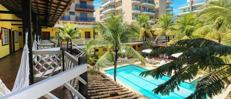 A hotel with a swimming pool, palm trees, and a view of other buildings.