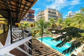 Un hôtel doté d’une piscine, de palmiers et offrant une vue sur d’autres immeubles.