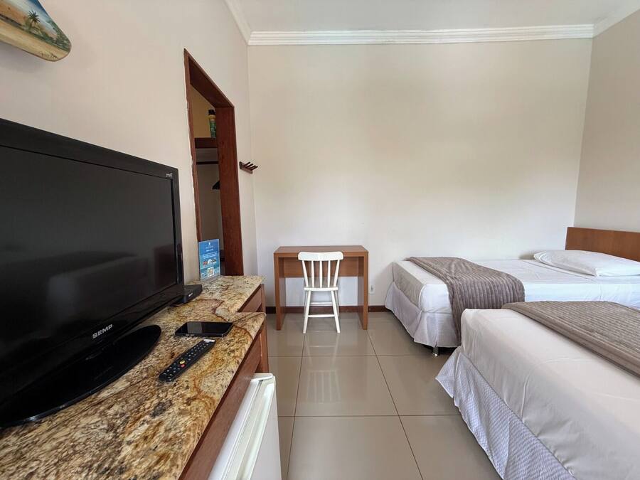 Una habitación de hotel con televisión, escritorio, silla y dos camas.