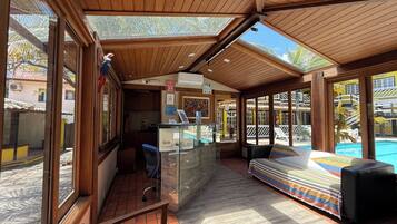 A covered outdoor seating area with a pool view, wooden ceiling, and a counter with a menu.