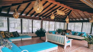 A covered outdoor seating area with blue cushions, wicker furniture, and hanging light fixtures.