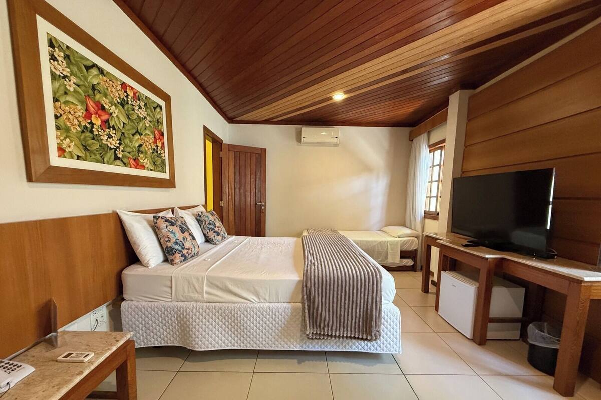 Une chambre à coucher avec un lit, une table de chevet, une télévision et un tableau au mur.
