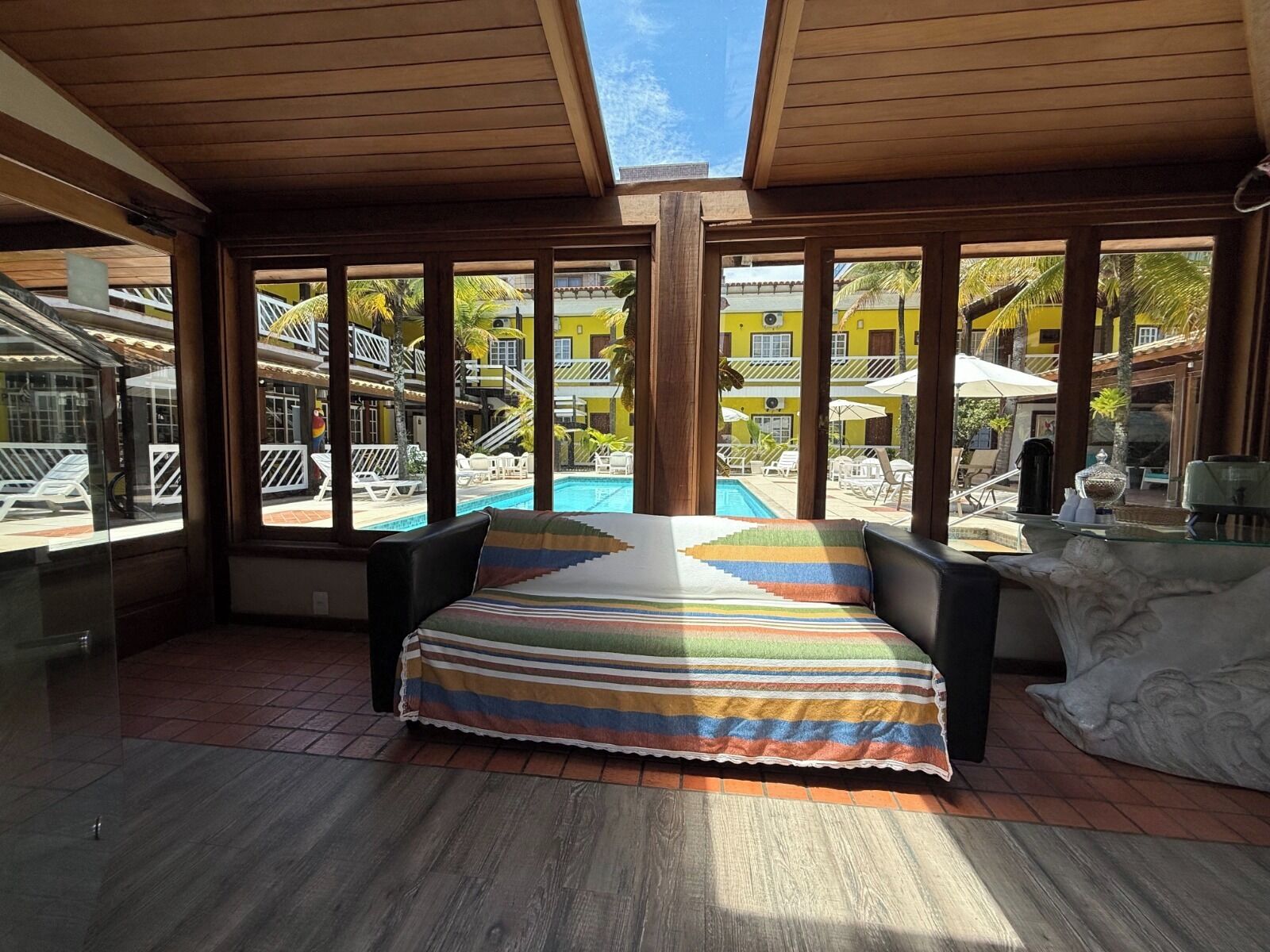 A room with a large window overlooking a pool and a yellow building.