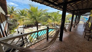 A covered outdoor area with a pool, palm trees, and a hammock.