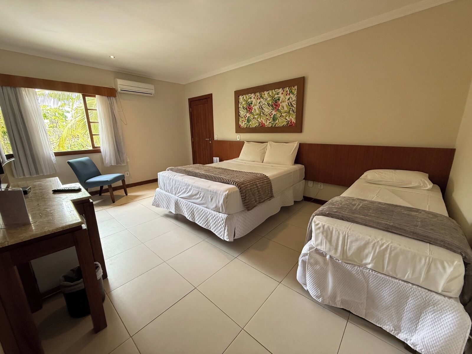 A hotel room with two beds, a desk, a chair, and a window with curtains.