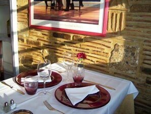 A table set for two with wine glasses, water glasses, and a red flower centerpiece. - Auberge de l'Abbaye (Le Bec-Hellouin)