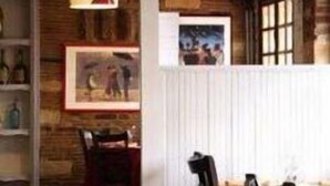 Un intérieur rustique avec des poutres apparentes, une fenêtre à cadre blanc et un luminaire suspendu.