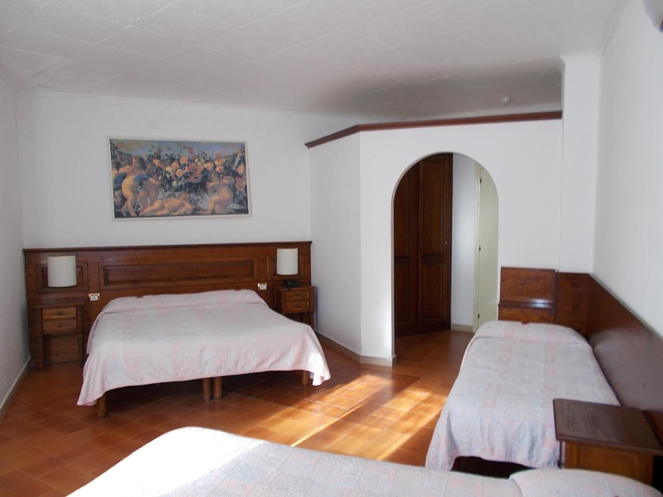 A bedroom with two beds, a wooden headboard, a painting on the wall, and a wooden wardrobe.
