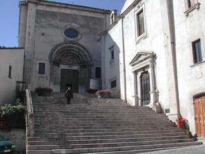 A building with a grand entrance, a staircase leading up to it, and a person descending the stairs. - Albergo del Sole (Roccaraso)