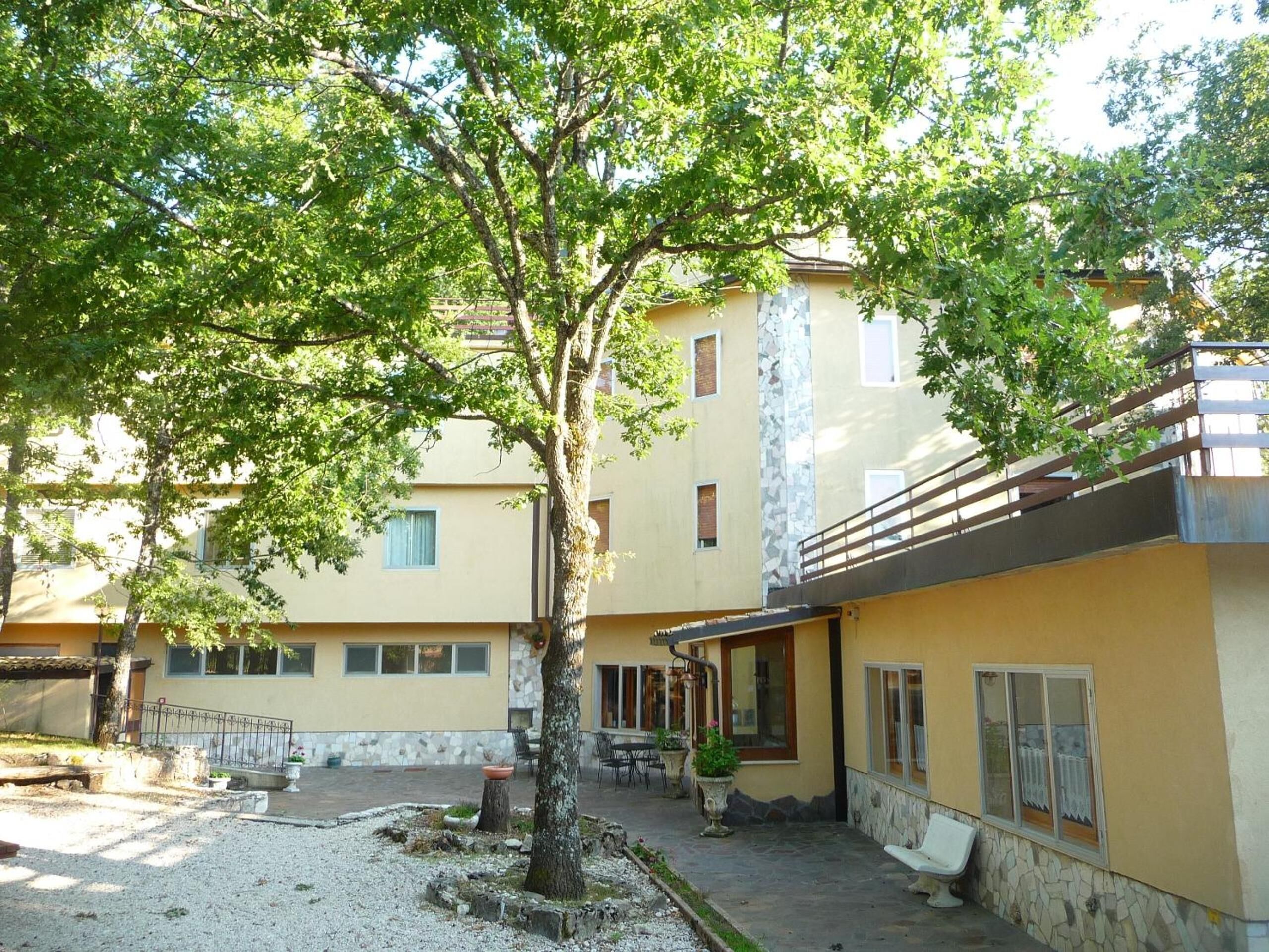 Une cour avec un arbre, des sièges extérieurs et un bâtiment doté de nombreuses fenêtres et de balcons.