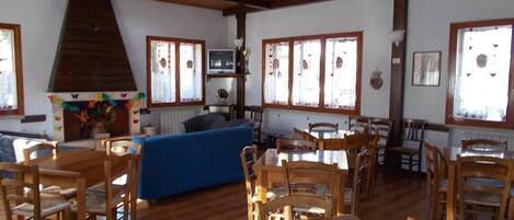 A cozy room with wooden furniture, a fireplace, and large windows.