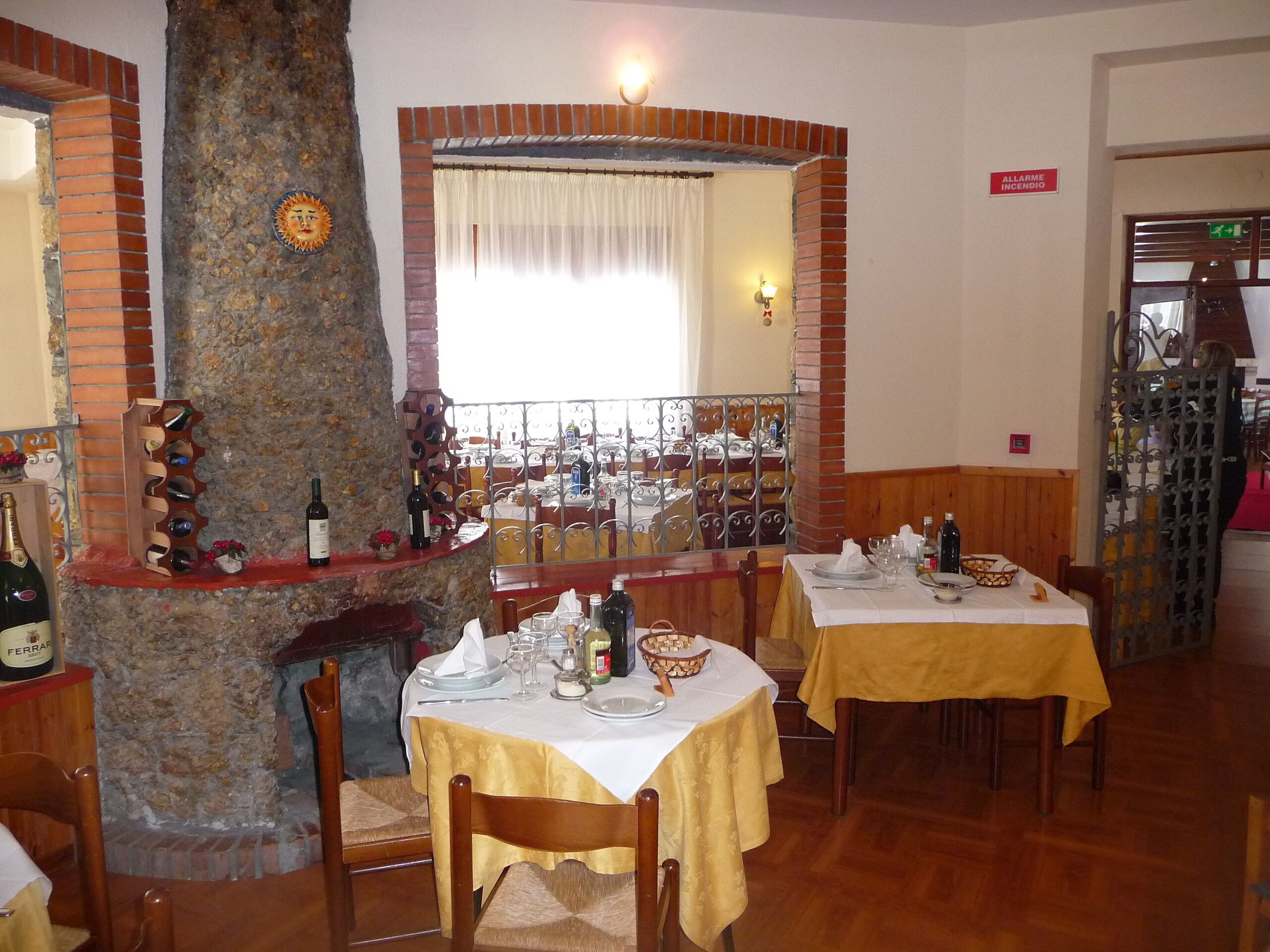 Un ristorante con pareti in mattoni, un pilastro in pietra e diversi tavoli apparecchiati.