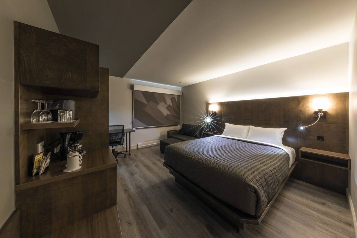Une chambre d’hôtel moderne avec un grand lit, un bureau équipé d’une machine à café et une bibliothèque.