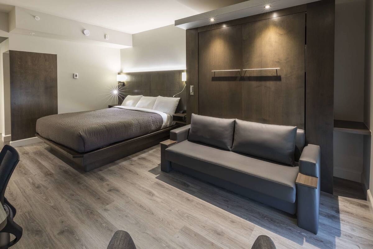 Une chambre moderne comprenant un lit, un canapé, un bureau et une armoire.