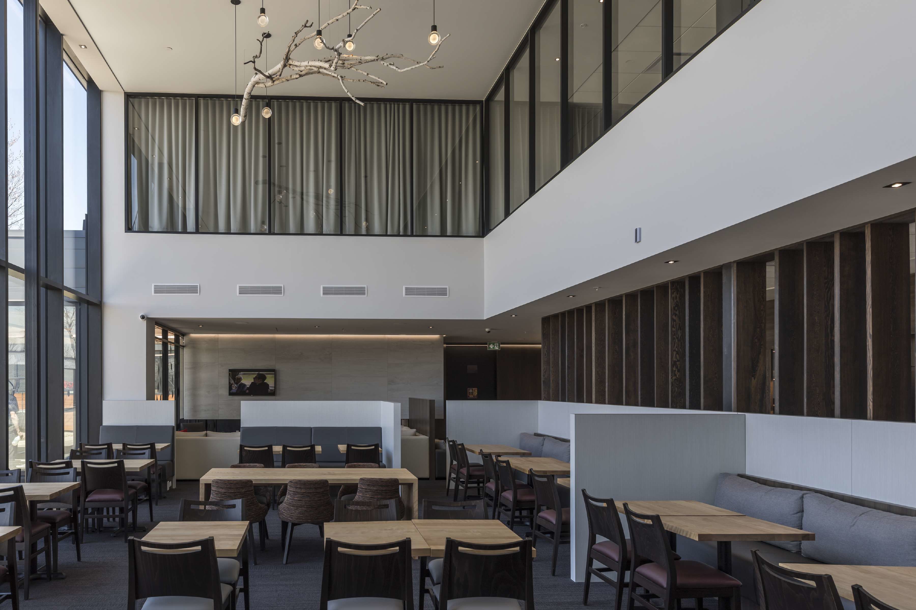 A modern restaurant with high ceilings, large windows, and a mix of seating options including tables and booths.