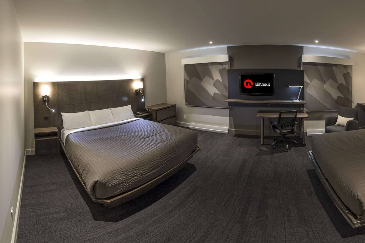 Une chambre d’hôtel moderne équipée de deux lits, d’un bureau, d’une télévision et d’une armoire.