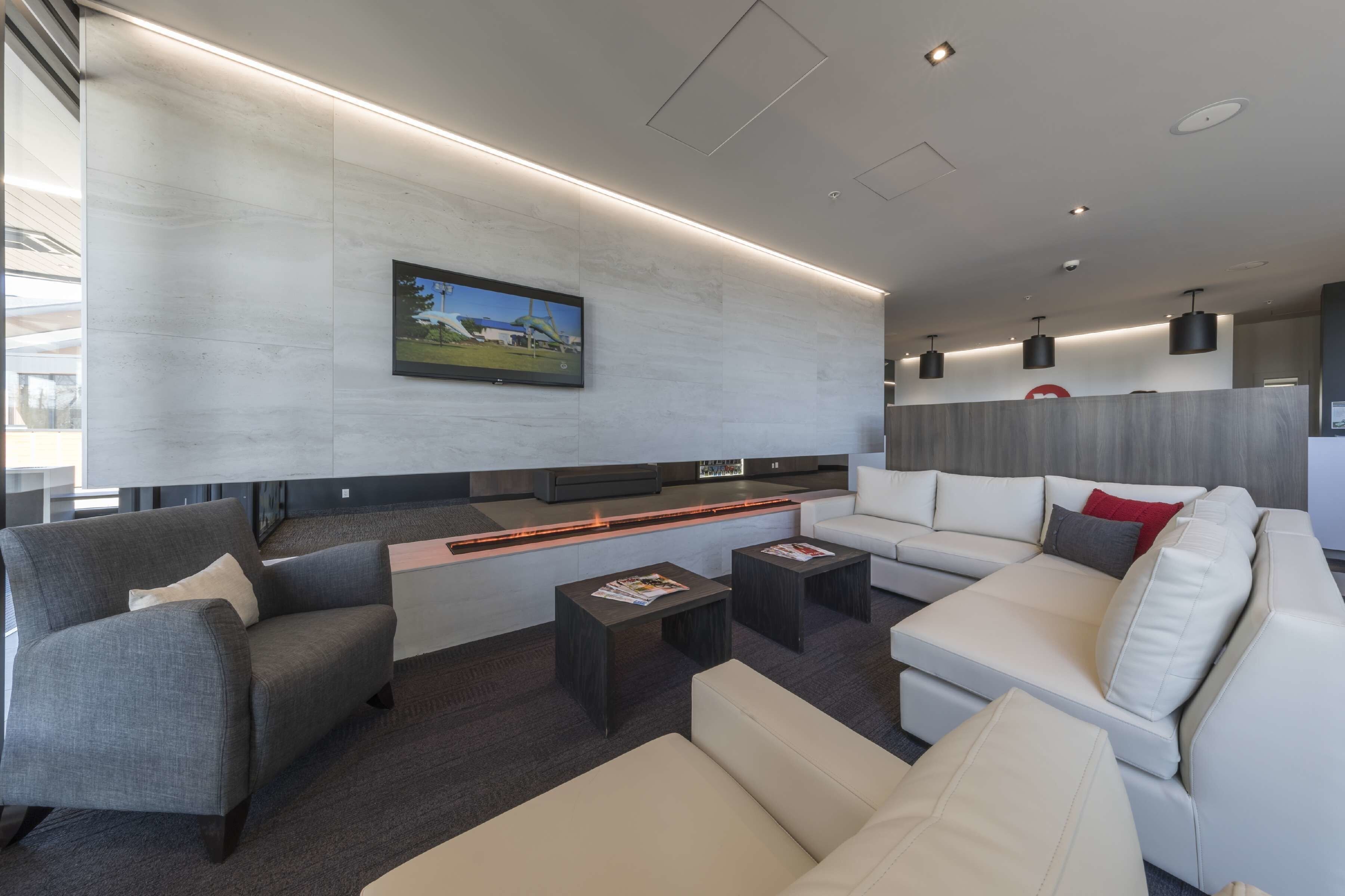 A modern living room with a sofa, armchairs, a coffee table, and a flat-screen TV mounted on the wall.