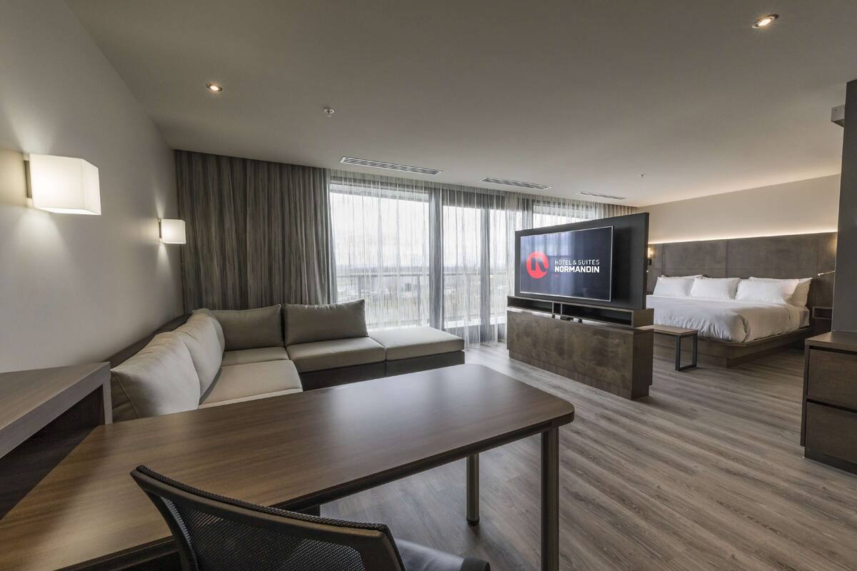 Une chambre d’hôtel moderne équipée d’un canapé, d’une table à manger, d’un téléviseur et d’un lit.