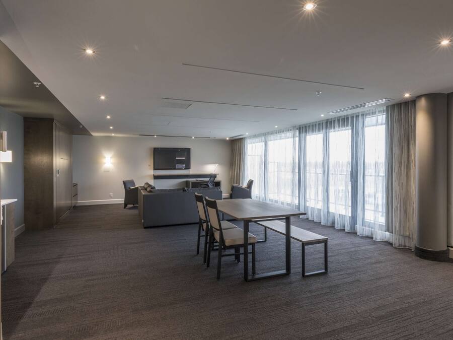 A modern conference room with a large table, chairs, a sofa, and a TV.
