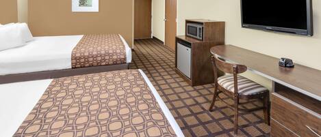 Habitación de hotel con dos camas, un escritorio, microondas, televisor y alfombra estampada.