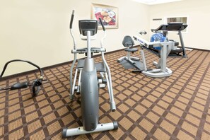 A fitness room with cardio machines, a patterned carpet, and a framed picture on the wall. - Microtel Inn & Suites by Wyndham Ozark (Ozark)