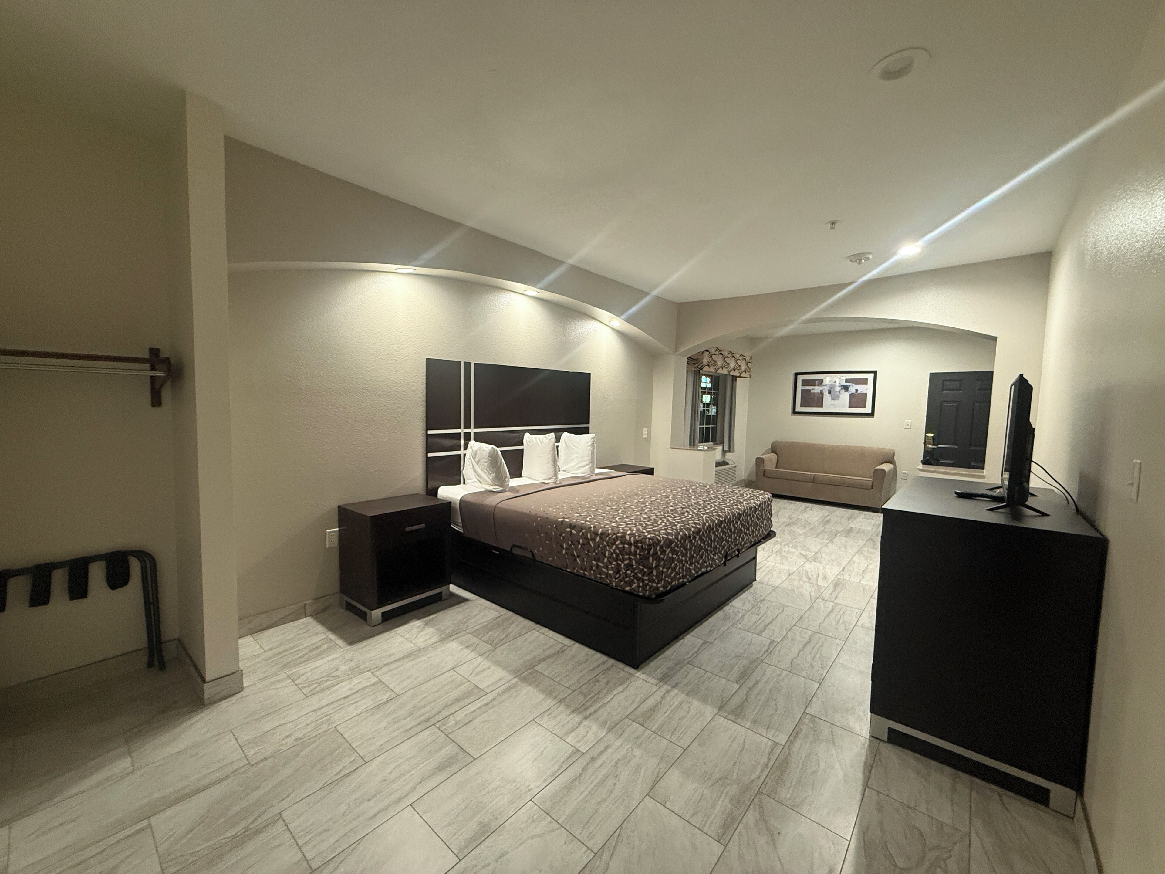 Un dormitorio moderno con una cama, mesitas de noche, un aparador y un televisor.