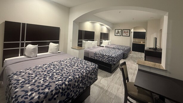 Ein Hotelzimmer mit zwei Betten, einem Schreibtisch und einem Stuhl. An der Wand befindet sich ein Spiegel und ein kleiner Tisch.