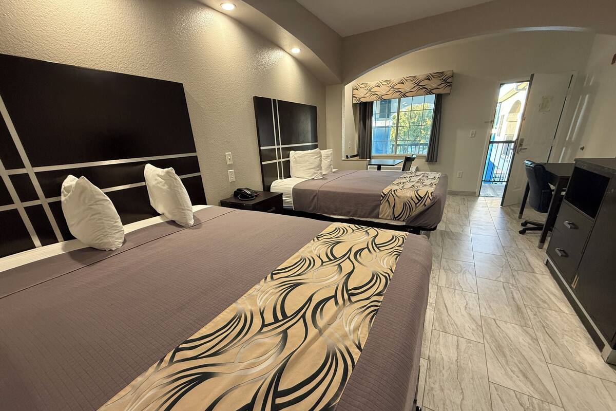 A modern hotel room with a large bed, a desk, and a view of the outdoors.