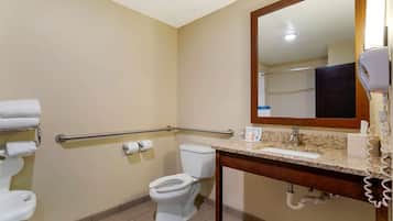 A bathroom with a toilet, hand dryer, and handrails.
