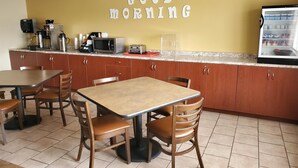 Ein kleines Café mit einem Schild ‚Good Morning‘, einer Kaffeemaschine, einer Mikrowelle und einem Kühlschrank.